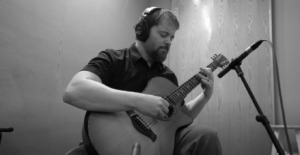 Stephen Vesolich, the creator of The Mountains Surround, playing guitar