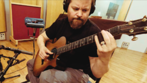 Stephen Vesolich with a wooden slide on an acoustic guitar for Psalm 129 (Greatly Oppressed)